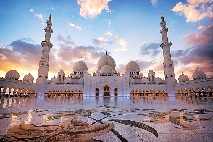 Experience the splendor of Abu Dhabi's architectural treasures as the stunning Sheikh Zayed Grand Mosque gleams under the shifting hues of the sky inviting exploration and admiration.